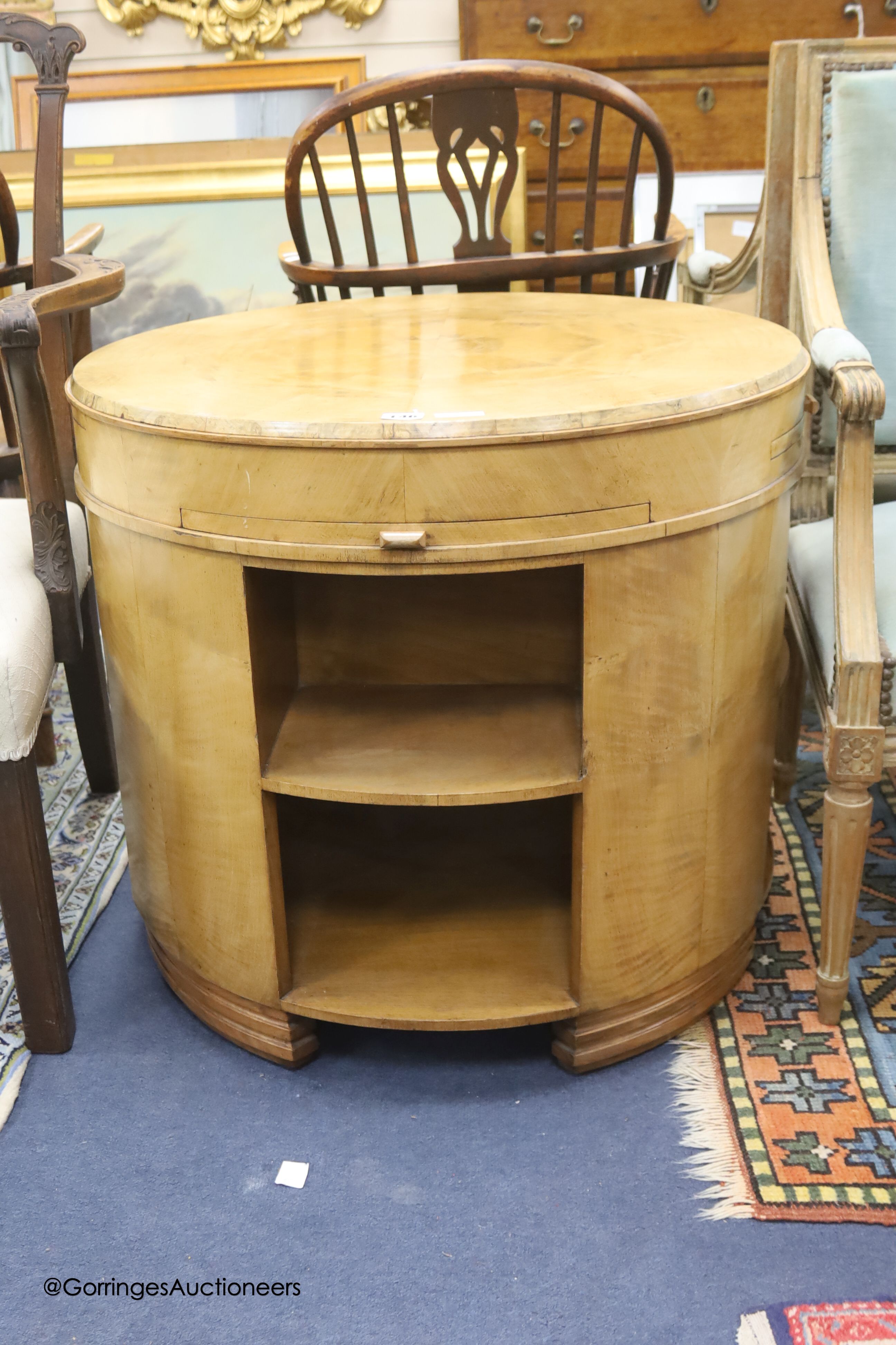 An Art Deco circular maple and bird's eye maple centre table with drawer leaves and open shelves